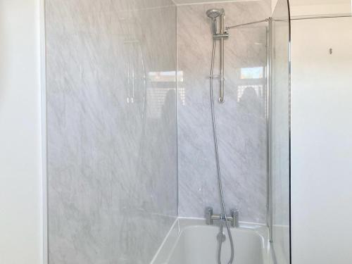 ducha con puerta de cristal junto a la bañera en The Duck House en Wool