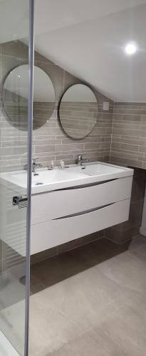 baño con lavabo blanco y 2 espejos en Le Béluga spa Nantes Bouguenais Aéroport en Bouguenais