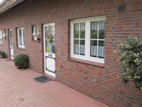 a brick house with a white door and windows at Ferienhaus Kickler, FeWo Vermittlung Nordsee in Dangast