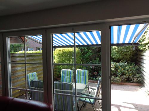 a screened in porch with chairs and a table at Ferienhaus Kickler, FeWo Vermittlung Nordsee in Dangast