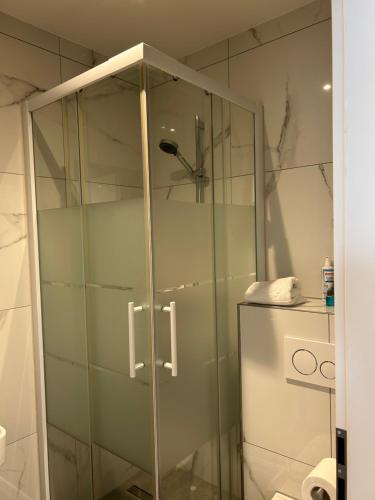 een douche met een glazen deur in de badkamer bij M & M Hotel in Oyten