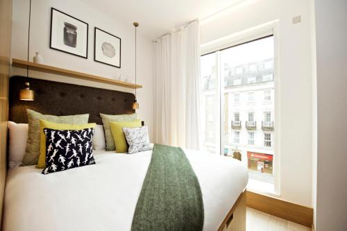 a bedroom with a large bed and a large window at Wilde Aparthotels London Covent Garden in London