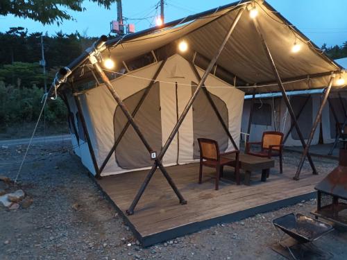 Tienda de campaña con sillas y luces en una terraza de madera en Club Lespia in Taean en Taean