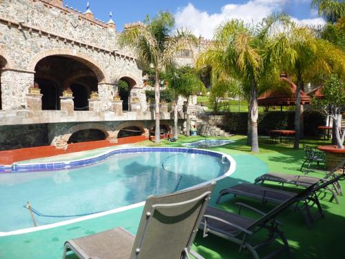 a swimming pool in front of a building with chairs at Hotel Castillo de Santa Cecilia in Guanajuato