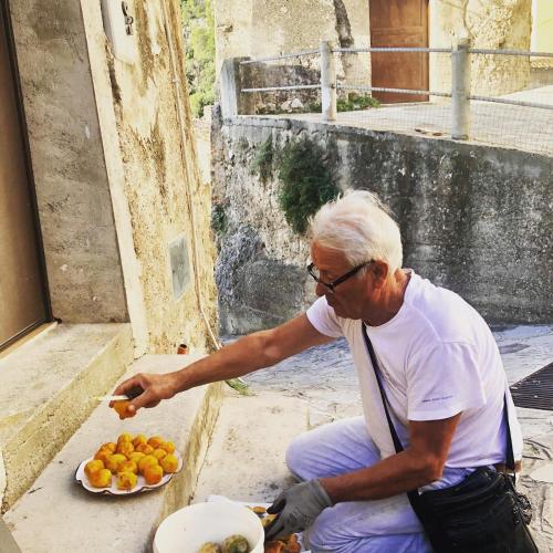 a man sitting on the ground with a plate of oranges at La Magara in Civita