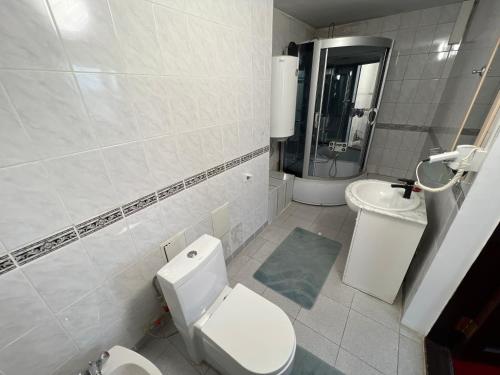 a white bathroom with a toilet and a sink at Яссы hotel, Turkistan in Türkistan