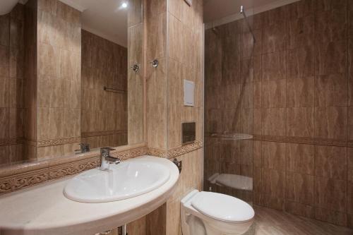 La salle de bains est pourvue d'un lavabo et de toilettes. dans l'établissement Апартаменти Варна Саут на плажа - Varna South Apartments on the beach, à Varna