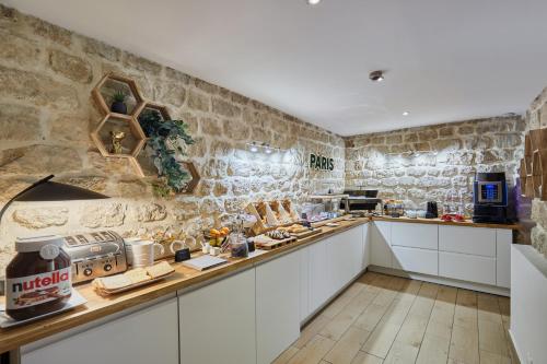 - une cuisine avec des placards blancs et un mur en pierre dans l'établissement Hotel Berne Opera, à Paris