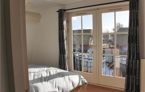 ブリューケレンにあるPet Friendly Home In Breukelen With House Sea Viewのベッドルーム1室(大きなガラスドア、バルコニー付)