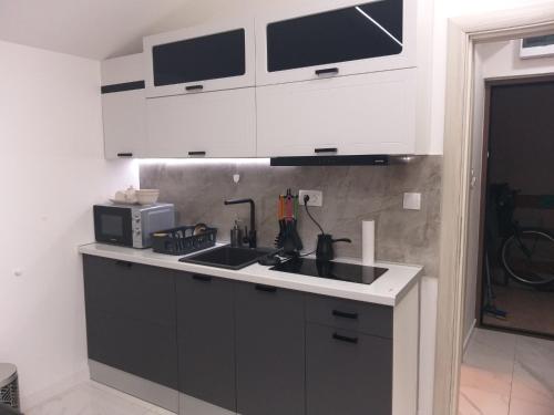 a kitchen with black and white cabinets and a sink at Studio 033 in Budva