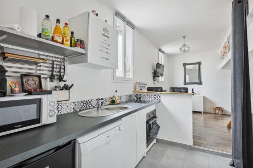 une cuisine avec un évier et un micro-ondes dans l'établissement Au coeur du triangle d'or de Versailles, à Versailles