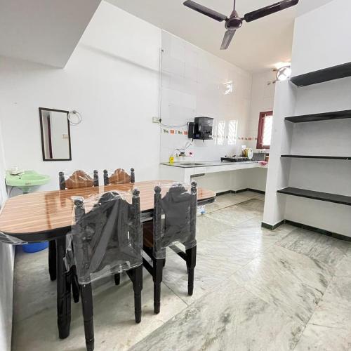 uma cozinha com uma mesa de madeira e cadeiras pretas em WHITE HOUSE - 3BHK Elegant Apartment em Coimbatore