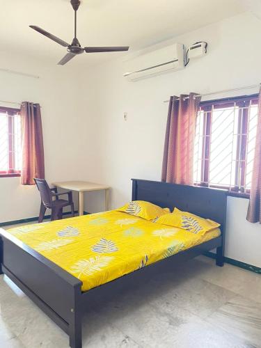 a bedroom with a bed with yellow sheets and a table at WHITE HOUSE - 3BHK Elegant Apartment in Coimbatore