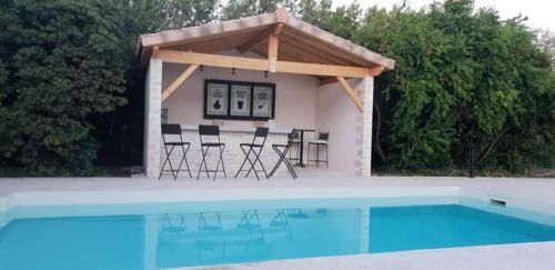 a house with chairs and a swimming pool at MAS TAREAU LE DAMIER in Beaucaire