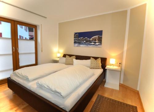 ein Schlafzimmer mit einem Bett mit weißer Bettwäsche und zwei Lampen in der Unterkunft Ferienhaus Trettach in Oberstdorf