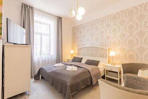 Schlafzimmer mit einem Bett, einem TV und einem Stuhl in der Unterkunft Hotel Amadeus in Budweis