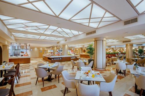 un restaurante con mesas y sillas y una cafetería en Louis Ledra Beach en Pafos