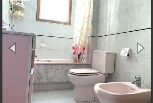 uma casa de banho com um WC, um lavatório e uma janela em Apartamento con terraza en 1ª linea lateral a mar em Calafell