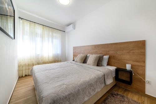 a bedroom with a large bed with a wooden headboard at Apartman Ivana in Šibenik