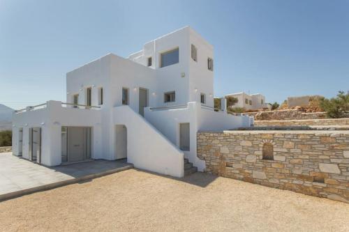 a large white house with a stone wall at Solasta Residence in Márpissa