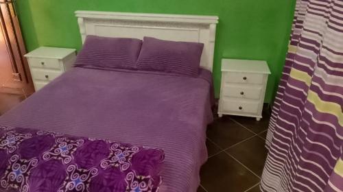1 dormitorio con 1 cama de color púrpura y 2 mesitas de noche en TOP Appartement, en Aourir
