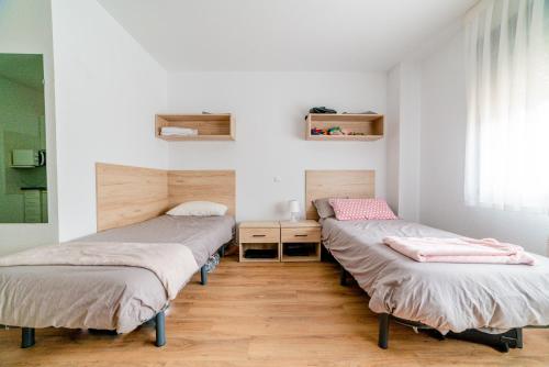 twee bedden in een kamer met witte muren en houten vloeren bij Micampus Logroño in Logroño