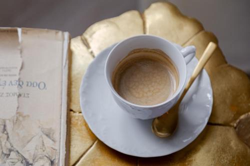 a cup of coffee on a plate next to a book at Residenza di Fedralia in Nafplio