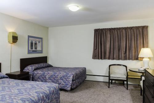 a hotel room with two beds and a chair at The Cavalier Inn in Winnipeg