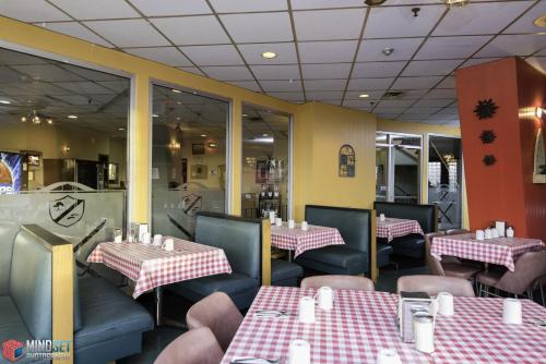 a restaurant with tables and chairs with red and white tablecloths at The Cavalier Inn in Winnipeg