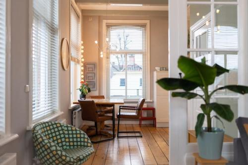 a dining room with a table and chairs and windows at Sfeervol verblijf in oude gemeentehuis Eenrum. in Eenrum