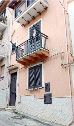 - un bâtiment rose avec un balcon et une fenêtre dans l'établissement La casa dei nonni piano terra, à Montallegro