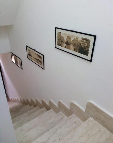 un escalier avec deux photos sur un mur blanc dans l'établissement La casa dei nonni piano terra, à Montallegro