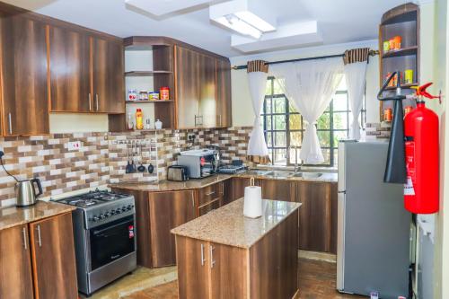 cocina con armarios de madera y nevera en Villa Winga Deluxe Hotel, en Kisumu