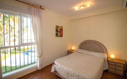 - une chambre avec un lit et une grande fenêtre dans l'établissement Adosado familiar frente a la piscina - Palm Beach ALBERT VILLAS Alcossebre, à Alcossebre