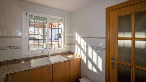 La salle de bains est pourvue d'un lavabo et d'une fenêtre. dans l'établissement Adosado familiar frente a la piscina - Palm Beach ALBERT VILLAS Alcossebre, à Alcossebre