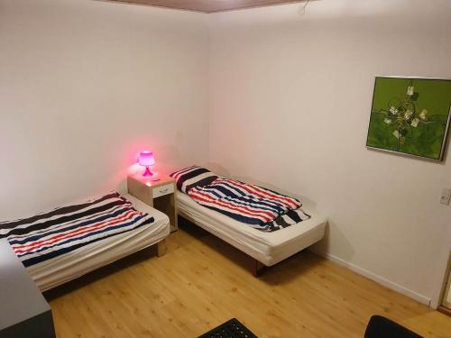 two beds in a room with a lamp on a table at Rundvejen Guest House in Aalborg