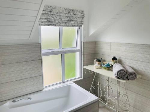 łazienka z wanną i oknem w obiekcie Quaint Gowrie Village Apartment w mieście Nottingham Road