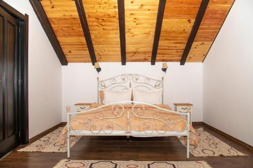 Ce lit se trouve dans un dortoir doté d'un plafond en bois. dans l'établissement Cabana Perla Durau, à Durau