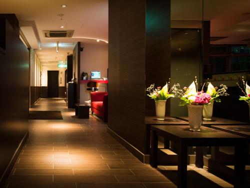 a corridor of a hotel lobby with flowers on tables at SUPER HOTEL Tokyo Akabane Station Higashiguchi Ichibangai in Tokyo