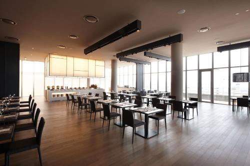 a dining room with tables and chairs and windows at Shilla Stay Jeju Airport in Jeju