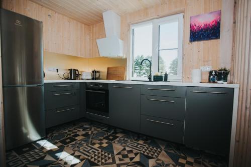 a kitchen with a stainless steel refrigerator and a window at Brīvdienu māja Saule in Mērsrags