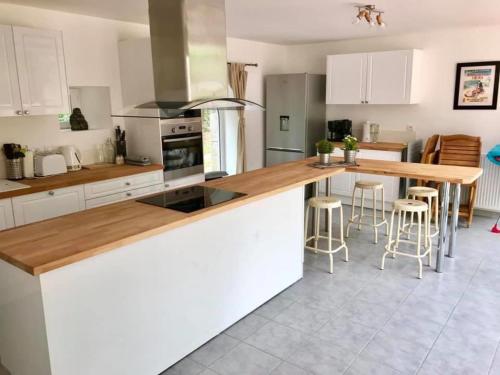 a kitchen with white cabinets and a wooden counter top at 6Bed-Sleeps12-GroupRetreat-YogaStudio-PetFriendly in Feugères