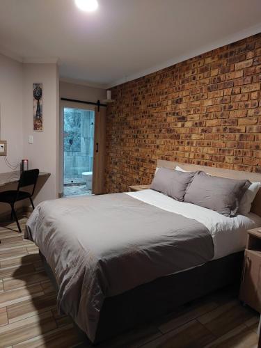 Un dormitorio con una pared de ladrillo y una cama grande en Twins Guest House Astoni, en Vanderbijlpark