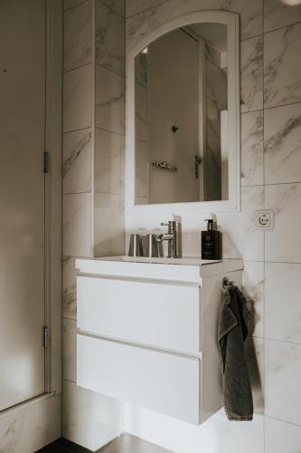 a white bathroom with a sink and a mirror at B&B Appartementen Smedery in Nijmegen