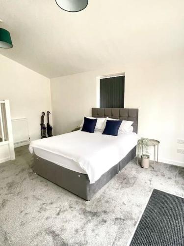 a bedroom with a large white bed with blue pillows at 2.Superb Serviced Apartment - free on road parking in Birmingham