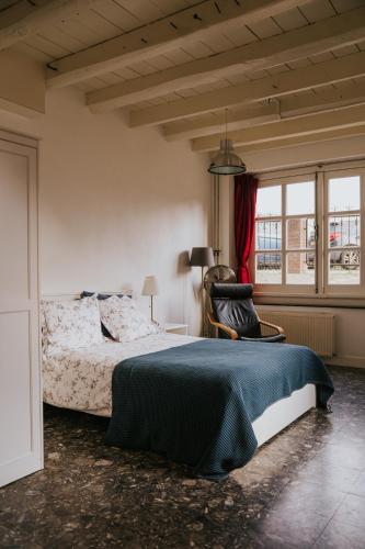 a bedroom with a bed and a chair and a window at B&B Appartementen Smedery in Nijmegen