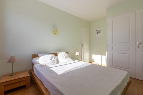 una camera da letto bianca con un letto con lenzuola e cuscini bianchi di Patufet - Charmante maison 6 personnes a Fontrabiouse