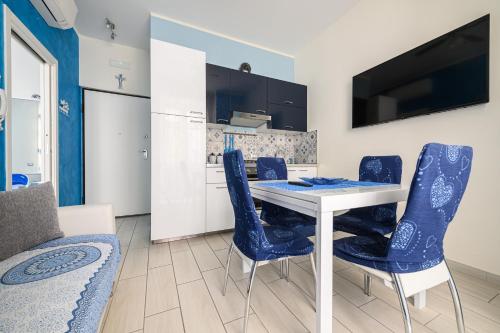 uma sala de jantar com uma mesa branca e cadeiras azuis em Appartamento Luci d'Artista em Vietri