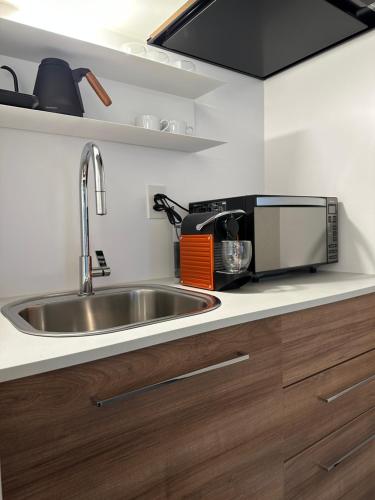 a kitchen with a sink and a microwave at Hotel 草石庵 in Osaka