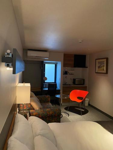 a living room with a couch and a red chair at Hotel 草石庵 in Osaka
